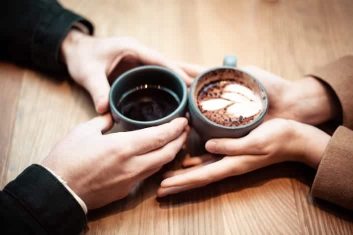 Couple holding hands with their coffee